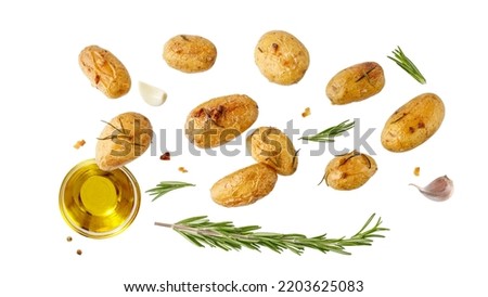 Fresh baked small whole potatoes with olive oil, rosemary and garlic flying isolated on white background.