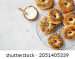 Fresh baked sourdough New York style bagels with cream cheese on light gray table, top view