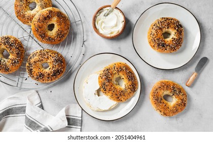 Fresh baked sourdough New York style bagels with cream cheese on light gray table, top view