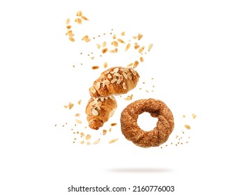 Fresh baked turkish simit sesame bagel, french butter almond nut croissants flying falling with seeds, flakes and crumbs isolated on white background. Pastry shop card