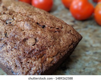 Fresh baked zucchini bread with tomatoes in the background.