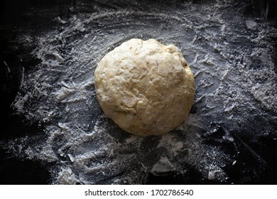 Fresh Ball Of Pizza Dough On A Lightly Floured Dark Countertop. Perfect Recipe For Family Pizza Night For Couples And Kids. Recipe Made From Sourdough Discard