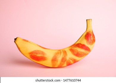 Fresh banana with red lipstick marks on pink background. Oral sex concept