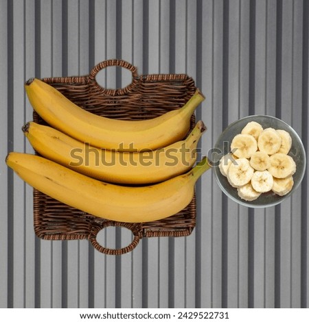 Fresh bananas arranged in a wicker basket alongside a bowl of chopped bananas. Healthy and delicious fruit concept. Copy space available.