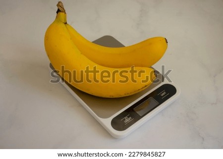 Fresh bananas, kitchen scales on a light background