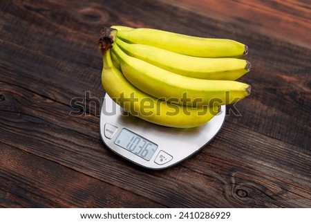 Fresh bananas, kitchen scales on a wooden table