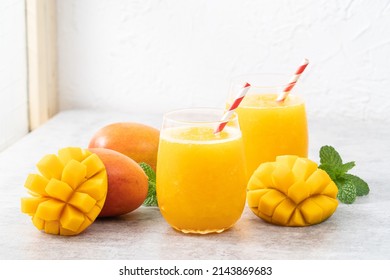 Fresh beautiful delicious mango juice. Close up design concept of smoothie cold drink in a glass cup with paper straw on gray table background. - Shutterstock ID 2143869683