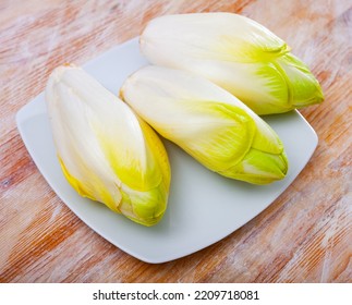 Fresh Belgian endive head (Witloof chicory) on wooden surface - Shutterstock ID 2209718081