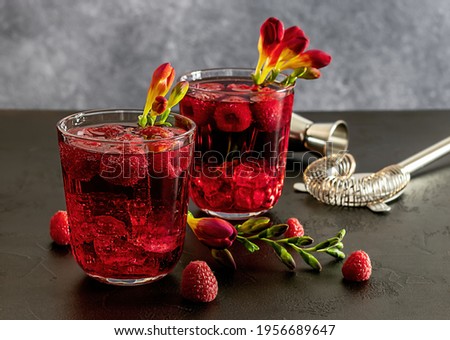 Fresh berries cocktail with gin, raspberry, soda water, and ice in glass on dark background. Summer cold alcohol drink. copy space 