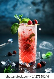 Fresh Berries Cocktail With Raspberry, Blackberry, Mint And Ice In Jar Glass On Dark Blue Background. Studio Shot Of Drink In Freeze Motion,  Flying Ice. Summer Cold Drink And Cocktail