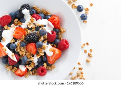 fresh berries, yogurt and homemade granola for breakfast, close-up, top view, horizontal - Powered by Shutterstock