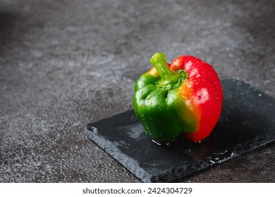 Fresh bicolor red and green bell pepper with water droplets on black concrete background. Fresh vegetables, vegan - Powered by Shutterstock