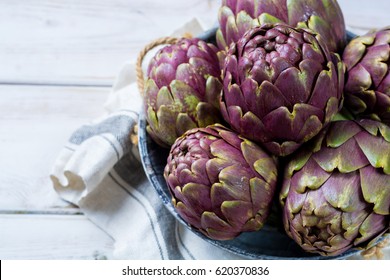 Fresh big Romanesco artichokes green-purple flower heads ready to cook seasonal food