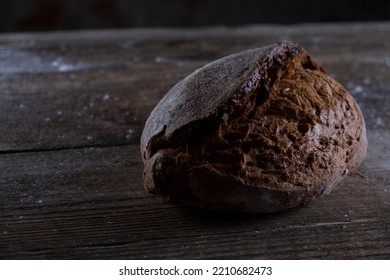 Fresh Black Bread On A Wooden Background Close-up. Low Key Still Life Concept Of Traditional Bakery. Rustic. High Quality Photo