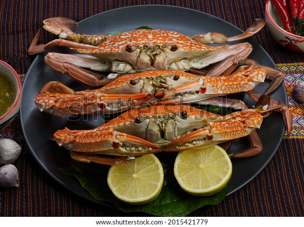 Fresh blue crab is placed on a black\
plate with Lemon . Thai crab.Free space for\
text.