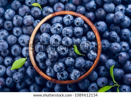 Fresh blueberry with drops of water in wooden bowl. Top view. Concept of healthy and dieting eating