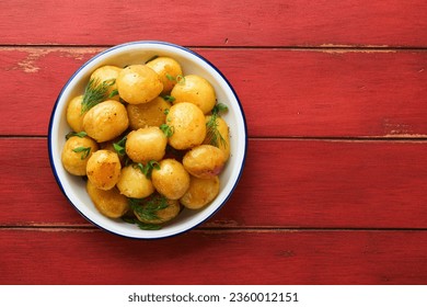 Fresh boiled new or young potatoes with butter, fresh dill and onions in white bowl on old red rustic wooden background. Tasty new boiled potatoes. Top view. - Powered by Shutterstock