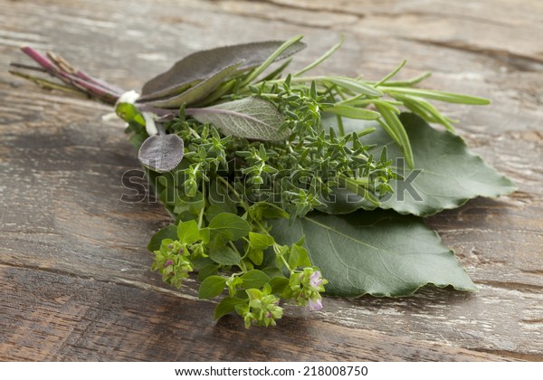 Fresh bouquet garni with different herbs on an old\
wooden table