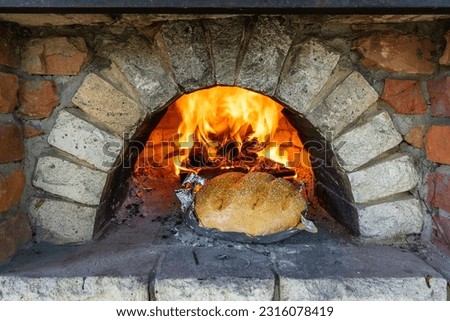 Fresh bread in a brick oven for cooking. Burning fire and bread in a stone oven, close up