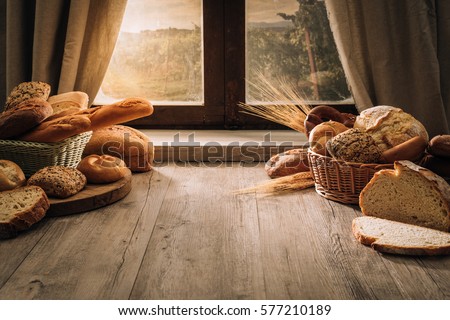 Fresh bread on the kitchen table in front of a window with a countryside panorama, healthy eating and traditional bakery concept