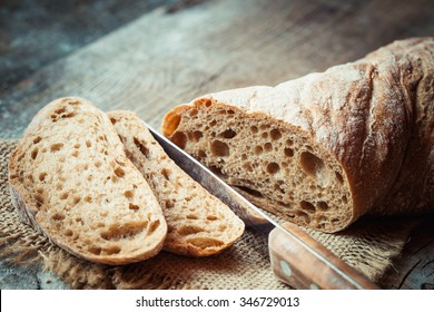 Fresh bread slice and cutting knife on rustic table - Shutterstock ID 346729013
