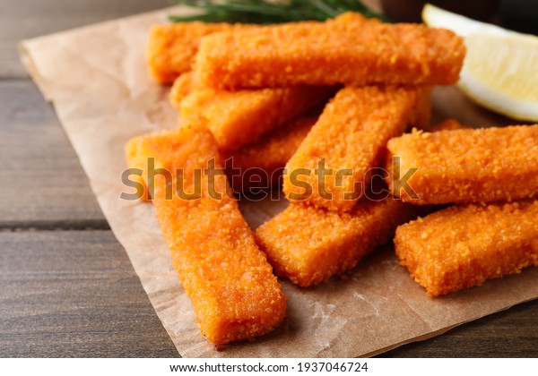 Fresh breaded fish fingers served on wooden\
table, closeup