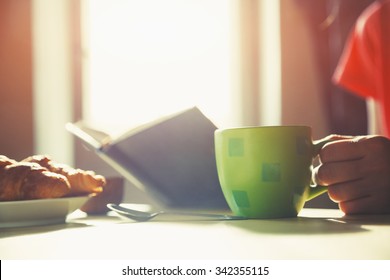 fresh breakfast with hot coffee and reading book in morning sunlight - Powered by Shutterstock