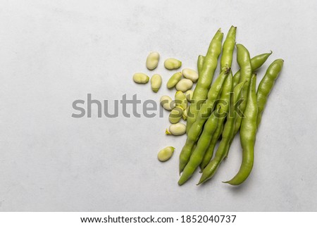 Fresh broad beans. Vertical shot with white rustic background