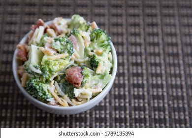 Fresh Broccoli, Bacon, And Cheese Salad Served In A White Bowl On A Brown Background (view From Above)