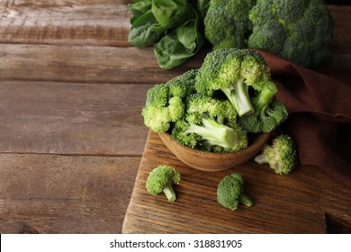 Fresh broccoli with spinach in bowl on wooden table close up - Shutterstock ID 318831905