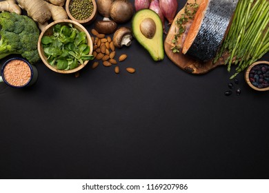 Fresh Broccoli, Veggies, Salmon Fillet Top View. Ginger, Avocado, Asparagus, Lentils, Basil, Almonds, Beans, Berries, Mushrooms And Onions On Black Background With Copy Space. Concept Of Healthy Food.