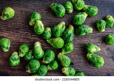 Fresh Brussels Sprouts Scattered On A Dark Wood Table: Overhead View Of Brussels Sprouts On A Rustic Wooden Background