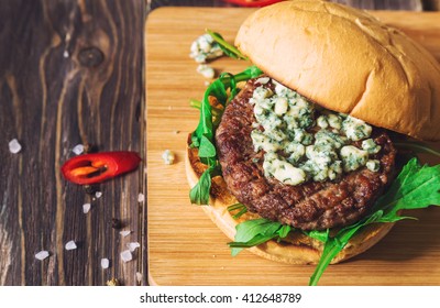 Fresh Burger With Blue Cheese And Arugula On Rustic Wooden Background. Top View. 