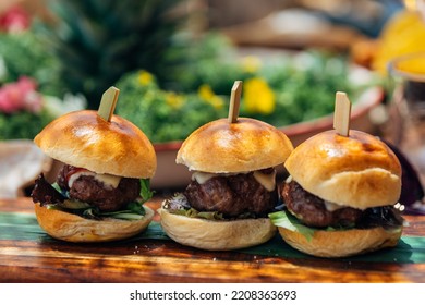 fresh burgers on a wooden table - Shutterstock ID 2208363693