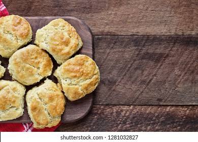 Fresh buttermilk southern biscuits or scones over a rustic wooden table shot from above. Top view.