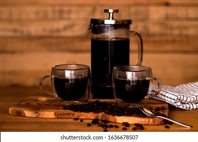 Fresh cafetiere coffee in glass mugs on a rustic wooden boards with coffee beans