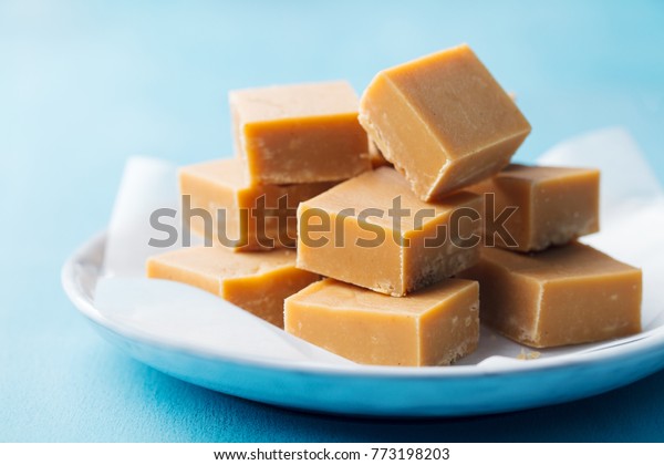 Fresh caramel fudge candies on a plate. Blue
background. Close up.