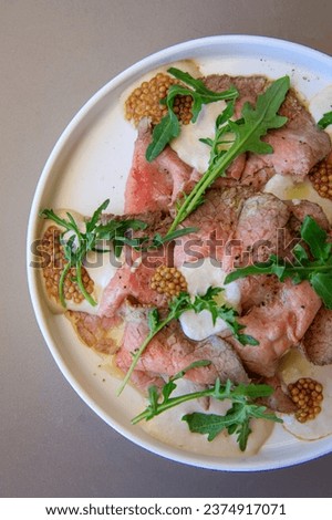 Fresh carpaccio with arugula on a plate in an Italian restaurant