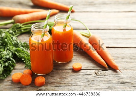 Fresh carrot juice in bottles on a grey wooden table