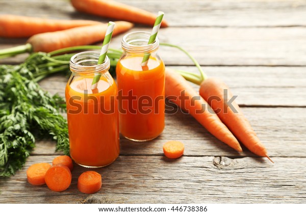Fresh\
carrot juice in bottles on a grey wooden\
table