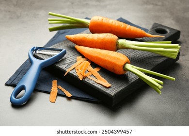 Fresh carrots, vegetable peeler and peels on gray textured table, closeup - Powered by Shutterstock