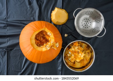 Fresh Carved Pumpkin On A Plastic Covered Table And Pumpkin Guts And Bowls
