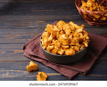 Fresh chanterelles in a green ceramic bowl on a dark wooden background. Wild mushrooms, ingredients for cooking. - Powered by Shutterstock