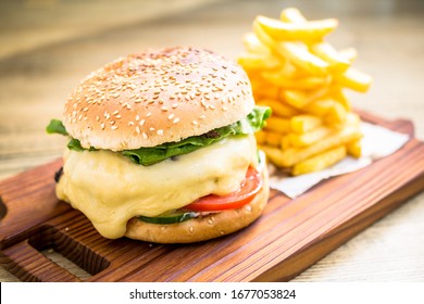 Fresh cheeseburger with melting cheese, tomatoes, cucumber, lettuce, homemade sauce and french fries - Powered by Shutterstock