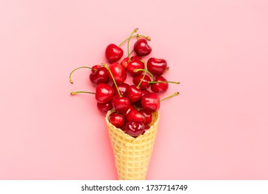 Fresh cherries in waffle cones Ice cream cone filled with fresh sweet cherry on pastel pink background. Top view. Copy space. Summer creative concept Flat lay Healthy food