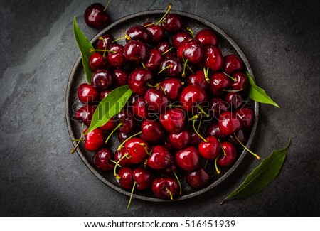 Fresh cherry on black plate on slate background. Top view, copy space