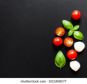 Fresh cherry tomatoes, basil leaf, mozzarella cheese on black slate stone chalkboard with copyspace. Healthy Italian traditional caprese salad ingredients. Organic Mediterranean food concept, flat lay