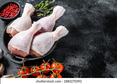 Fresh chicken drumsticks, legs with ingredients for cooking in a frying pan. Organic poultry meat. Black background. Top view. Copy space