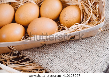 Fresh chicken eggs on a wooden rustic background. Fresh organic eggs in egg carton box. Close up of eggs in a nest box on a wooden table and sackcloth. Happy Easter and natural food background.