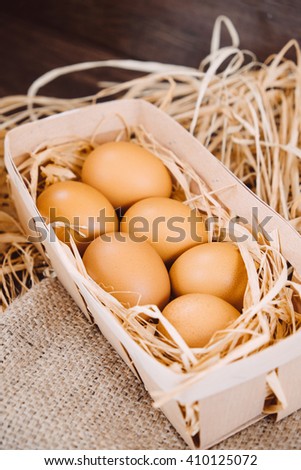 Fresh chicken eggs on a wooden rustic background. Fresh organic eggs in egg carton box. Close up of eggs in a nest box on a wooden table and sackcloth. Happy Easter and natural food background.